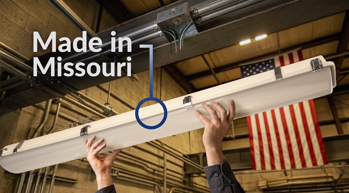Electrician holds vapor tight to wire fixture in a warehouse. USA flag in the background.